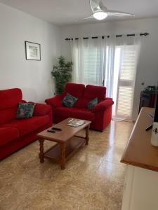 - un salon avec des canapés rouges et une table basse dans l'établissement Casa 64 - 2 Bedroom Penthouse At Las Marinas, Vera Playa, à Vera