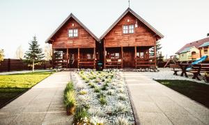 a log cabin with a garden in front of it at Baltic Summer - ośrodek dla rodzin z dziećmi in Rewa