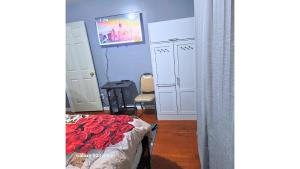 1 dormitorio con 1 cama y TV en la pared en Divine Guest House Room D. 6mins near EWR NEWARK Airport, 4mins to Penn Station / Prudential, en Newark