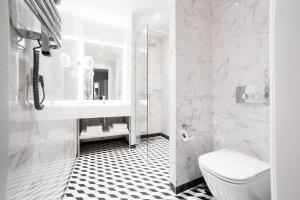 a white bathroom with a sink and a toilet at Modern Art Hotel - Maestro in Lviv