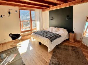 a bedroom with a bed and a large window at La Maison Abeil in LʼArgentière-la-Bessée