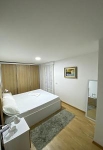 a bedroom with a large white bed and a mirror at Guest House Laci in Tirana
