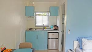 a small kitchen with blue cabinets and a sink at Ciri's Apartelle in Moalboal