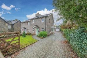 a house with a gate and a gravel driveway at Summerbank Cottage, luxury Lake District holiday home in Coniston in Coniston