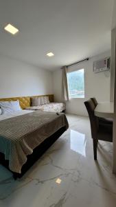 a bedroom with a bed and a desk and a window at Flat Jaguanum in Mangaratiba