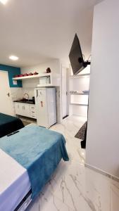 a white room with a bed and a kitchen at Flat Jaguanum in Mangaratiba