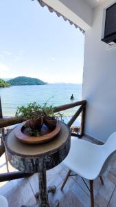 a table and a chair on a balcony with the ocean at Flat Jaguanum in Mangaratiba