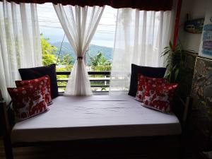 Cama en habitación con ventana y vistas en Country Bug Inn, en Tagaytay