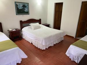 a bedroom with two beds with white sheets at Ecohotel La Casona Pereira in Pereira