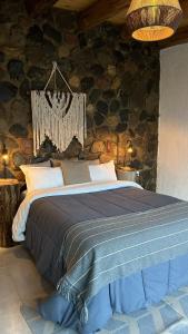 a bedroom with a large bed in a stone wall at Denmoza Eco Lodge in Potrerillos