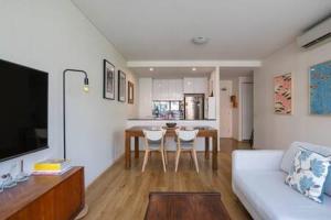 a living room with a white couch and a kitchen at Treetops Erskineville Apartment w Parking & Aircon in Sydney