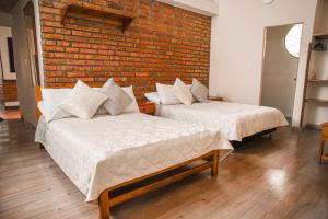 two beds in a room with a brick wall at Hotel Posada Campestre San Gil in San Gil