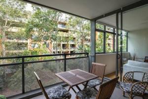 a room with a table and chairs and a balcony at Treetops Erskineville Apartment w Parking & Aircon in Sydney