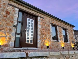 un edificio de piedra con puertas y ventanas de madera en Suite Rooms - Fine Living, en Vévi