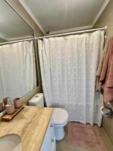 y baño con aseo y cortina de ducha. en Departamento Primera Línea Av. Del Mar La Serena en Coquimbo