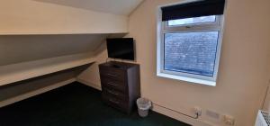 um quarto com uma cómoda, uma televisão e uma janela em ROOMS in WAKEFIELD CITY CENTRE em Wakefield