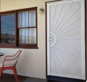 a white door with a red chair and a window at Chocolate Coyote in Joshua Tree