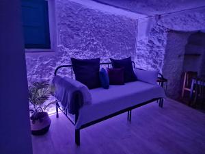 un divano viola in una stanza con un muro di pietra di BONITA CASA CUEVA CON JACUZZI a Paterna