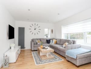 a living room with a couch and a clock on the wall at Clydfan, No 1 Trearddur Road in Trearddur
