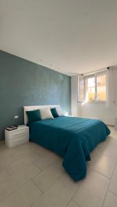 uma grande cama azul num quarto com uma janela em the smerald 2.2 em Alghero