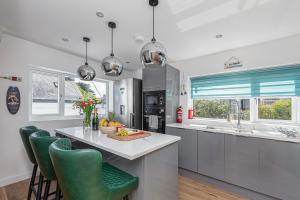 a kitchen with a large island with green chairs at Clydfan, No 1 Trearddur Road in Trearddur