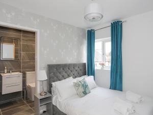 a bedroom with a bed with blue curtains and a sink at Clydfan, No 1 Trearddur Road in Trearddur