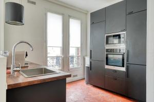 een keuken met roestvrijstalen apparatuur en een groot raam bij Big Maison 20 min Paris & Disney in Saint-Maur-des-Fossés