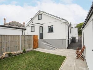 a white house with a fence and a yard at Clydfan, No 1 Trearddur Road in Trearddur