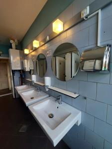 a bathroom with three sinks and mirrors on the wall at VV way - Lisica zvitorepka in Ljubljana