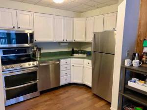 eine Küche mit weißen Schränken und einem Edelstahlkühlschrank in der Unterkunft Mt Green, Pool, Gym, Sauna, Hot tub 3br2b, in Killington Village