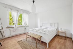 ein weißes Schlafzimmer mit einem weißen Bett und zwei Fenstern in der Unterkunft Homey Comfort in Oerlikon in Zürich