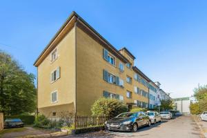 ein Apartmenthaus mit Autos auf einem Parkplatz in der Unterkunft Homey Comfort in Oerlikon in Zürich