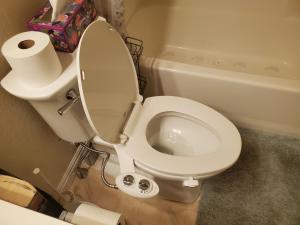 a white toilet in a bathroom with a roll of toilet paper at Not Vegas, But Close Enough in Boulder City