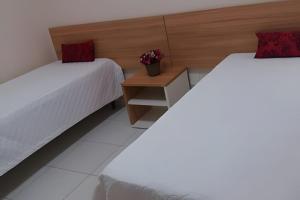 カルダス・ノバスにあるThermas Do Bosque By Bnbhostのベッド2台と花のテーブルが備わる客室です。