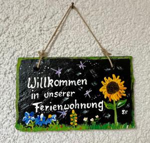 a sign hanging on a wall with a sunflower on it at Schöne Ferienwohnung im Grünen in Hainichen