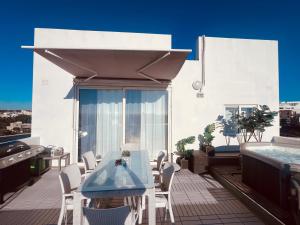 einen Balkon mit einem Tisch, Stühlen und einem Whirlpool in der Unterkunft LA88 SweetHome Penthouse with Jacuzzi in San Ġwann