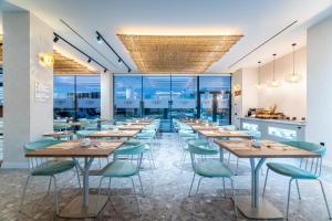 Hotel Málaga Vibes في مالقة: مطعم بطاولات خشبية وكراسي خضراء