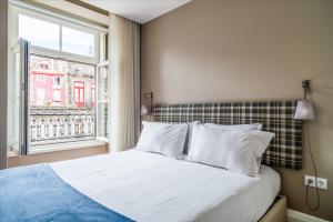 Cette chambre comprend un lit avec des oreillers blancs et une fenêtre. dans l'établissement Mouzinho 160, à Porto