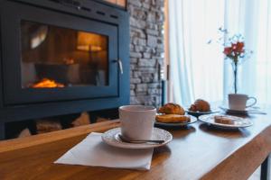 ein Tisch mit Tassen und Tellern mit Gebäck und ein Kamin in der Unterkunft RentUp - Las mejores vistas de San Martin, Volcan Lanin Chapelco y Lago Lacar in San Martín de los Andes