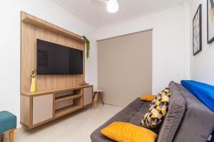 Una sala de estar con un sofá y un televisor de pantalla plana. en Aptos com excelente localização a 100m da PRAIA no Centro da Cidade com Garagem, Ar Condicionado, Portaria 24H, en Praia Grande