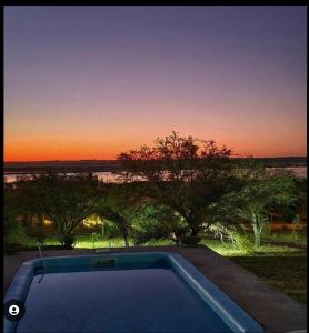 una piscina con puesta de sol en el fondo en Cuesta pampa casa de campo en Toay