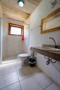uma casa de banho com um WC, um chuveiro e um lavatório. em Pousada do Mica em Praia do Rosa