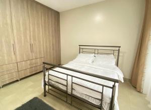1 dormitorio con 1 cama con sábanas blancas y almohadas blancas en Serene Edge, en Kampala