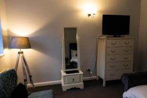 a bedroom with a television and a dresser with a mirror at The lodge at Carlton tavern free parking in York +23 photos