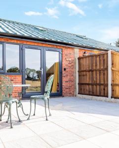 a patio with two chairs and a table and a building at Muntjac View, Beechcroft Barns, Cawston, Norfolk in Norwich