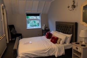 um quarto com uma cama com lençóis brancos e almofadas vermelhas em Carlton lodge at Carlton tavern free parking em York