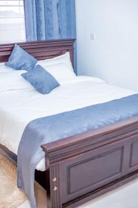 a bed with a wooden frame with a blue pillow at Captain Villa Narok in Narok