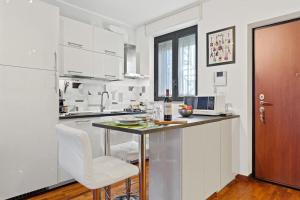 cocina blanca con mesa y sillas blancas en [Milano-M1] Rock House, en Milán