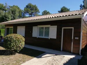 a small brown house with a door at Maison dans une bulle de verdure in Lacanau