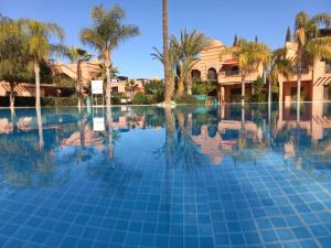 una piscina con palmeras y una casa en Atlas Views By Golf Resort, en Marrakech